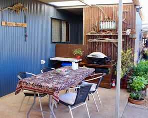 Out door dinning with webber bbq on covered  patio over looking gardens.