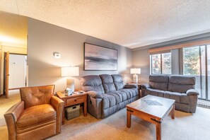 Living area with mounted flat screen TV, wood burning fireplace, and ample seating.