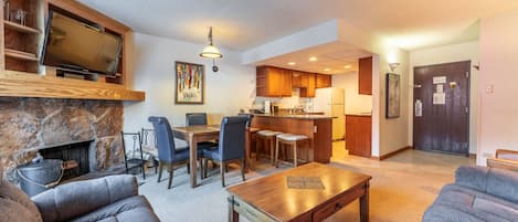 Living area with mounted flat screen TV, wood burning fireplace, and ample seating.