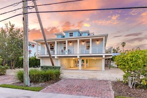 Front of the home during the twilight/sunset hour, located walking distance to the beach