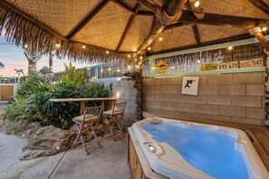 Clean well-maintained jacuzzi under custom tropical palapa with market lights.