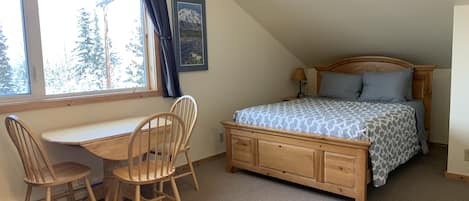 Queen bed and kitchen table with large bay window with mountain views.
