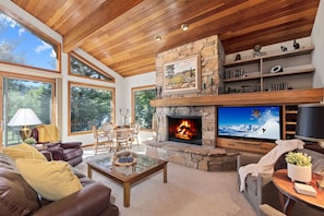 Living area with wood burning fireplace, television, game table & cozy seating 
