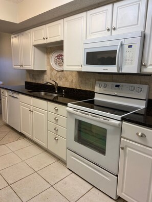 Bright kitchen with granite counters and Bosch dishwasher.