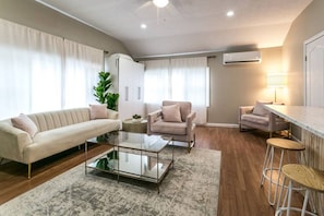 The cozy living room with a fireplace, couch, coffee table, and TV.