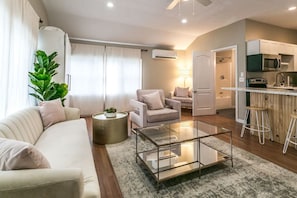 The cozy living room with a fireplace, couch, coffee table, and TV.