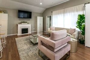 The cozy living room with a fireplace, couch, coffee table, and TV.