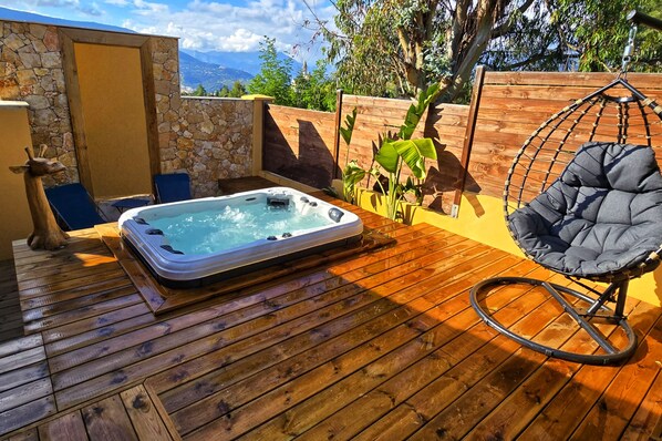 Patio: terrasse bois avec jacuzzi intégré. Parasol déporté, salon jardin