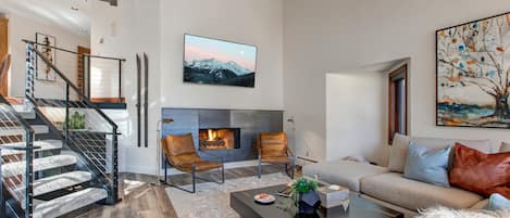 Living Room with over-sized plush sectional, beautifully modern decor, gas fireplace, 55" Samsung smart tv, and private balcony access