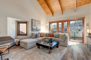 Living Room with over-sized plush sectional, beautifully modern decor, gas fireplace, 55" Samsung smart tv, and private balcony access