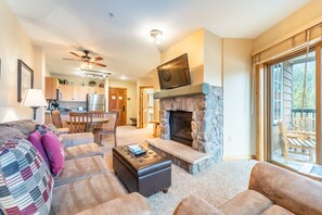 Living area with gas fireplace, mounted flat screen TV, queen sleeper sofa and access to the balcony.