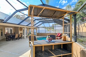 The gorgeous screened in porch holds a pool, hot tub, seating, and a bar.