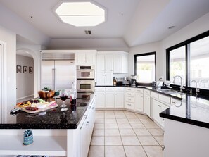 Fully equipped kitchen with stainless steel appliances, basic cooking essentials, dining table, and bright skylight!