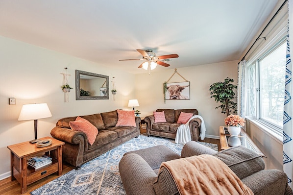 Spacious living room with lots of comfortable seating and natural sunlight.