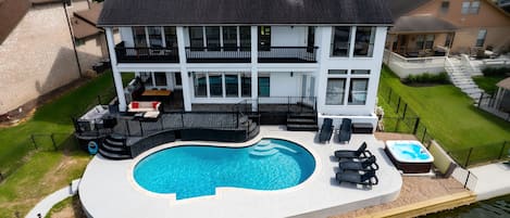 Waterfront with pool, hot tub, and outdoor kitchen. 