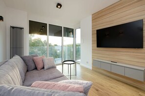 A spacious living room with a large grey sofa from where you can comfortably watch TV on the flat-screen TV.