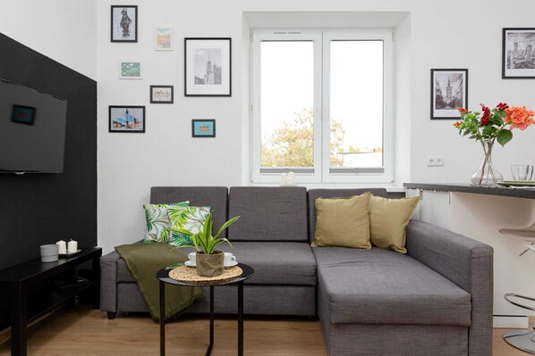 A bright living room with a grey corner sofa next to which there is a coffee table.