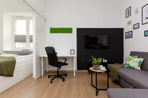 A view of the flat-screen TV hangs on the black wall next to which stands a desk and chair, an ideal area for working and studying in front of the computer.