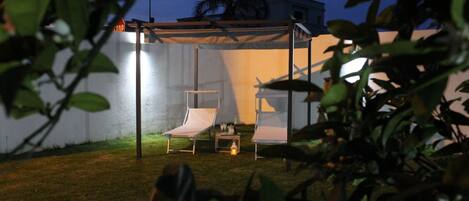 giardino a prato inglese con gazebo e lettini prendi sole di sera