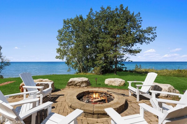 Gather with friends and family around the sandstone patio & firepit overlooking Lake Michigan at Costal Cottage part of the 100 Collection