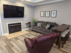  Living Area with a comfy recliner, hide-a-bed sofa, and table by large 75" TV