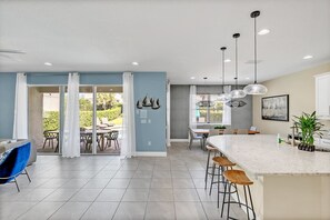 Enjoy your morning coffee with views of the lush backyard and pool through panoramic glass doors.
