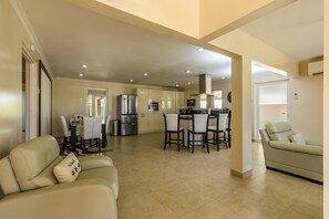 A living room filled with a comfortable sofa. There is an air conditioning unit and ceiling fan. There's a TV for entertainment and large curtains for privacy