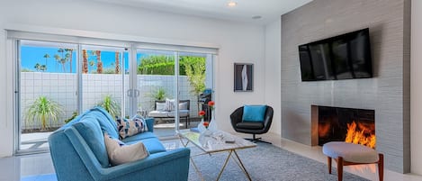 Living room with sleek gas fireplace and 55" Smart TV opens to private patio