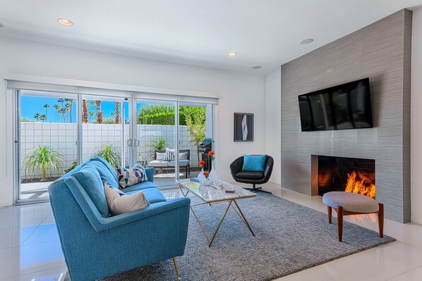 Living room with sleek gas fireplace and 55" Smart TV opens to private patio