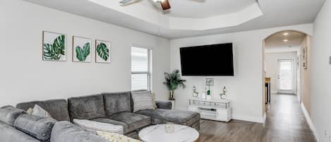 Spacious living room features a cozy sectional and a large flat screen TV