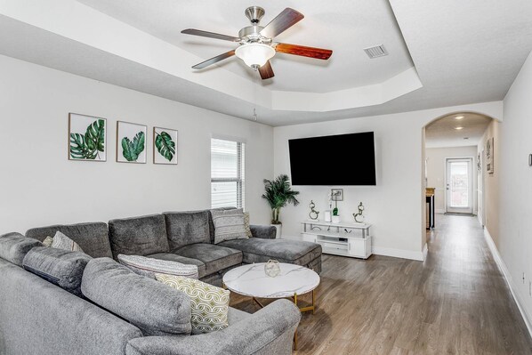 Spacious living room features a cozy sectional and a large flat screen TV