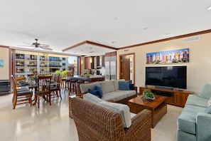 Living room with two couches and a chair around a 65” HD Smart TV, upgraded cable and high-speed internet.