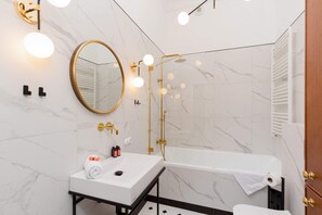 Modern bathroom with a bathtub and shower function, sink with mirror, toilet and washing machine.