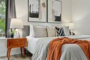 Unwind in the stylish primary suite with a luxurious king-size bed, mid-century accents, and soft, natural light for a peaceful night’s rest.
