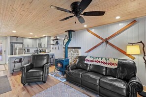 Homey Retreat: Create lasting memories in your personal haven with a comfy sofa, stylish coffee table, a warming gas stove, and a Smart TV for movie nights. Open the door to the outdoor deck for a touch of nature. 