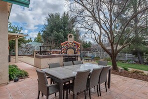 Outside patio with outdoor dining, BBQ, and pizza oven