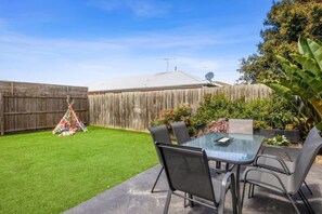 The fully fenced backyard with synthetic turf is safe and secure, ideal for children to play freely