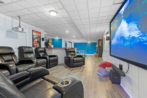 Lower level theatre area with projector, 100-inch screen, and surround sound.