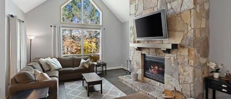 Spacious living room with Smart TV, Fireplace stocked with wood and vaulted ceilings.