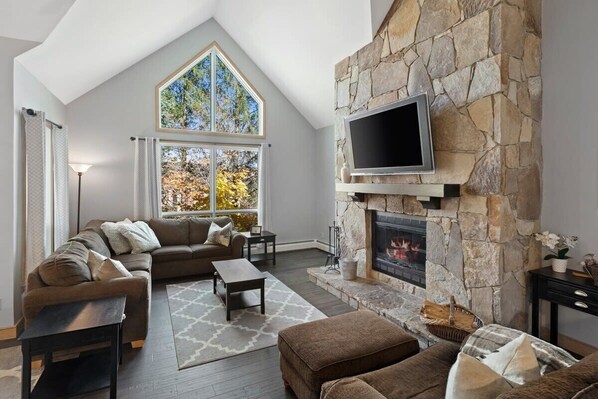 Spacious living room with Smart TV, Fireplace stocked with wood and vaulted ceilings.