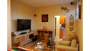Guests living room with TV and stereo. Opening eating nook with two stools.