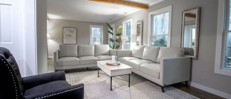 Downstairs lounging area with 60" tv, two 84" leather sofas, and reclining chair