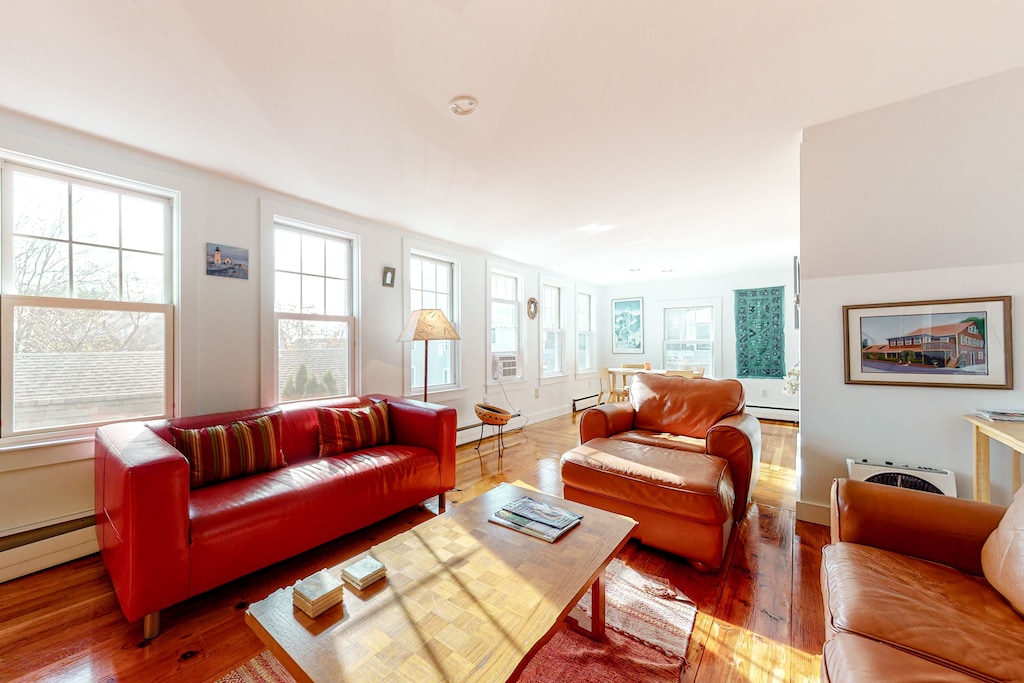 A living room in a vacation home in Ptown, Massachusetts has windows all along the wall allowing ample sunlight in.