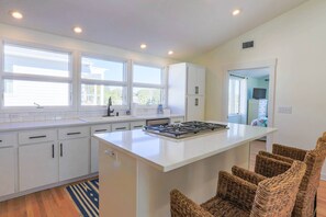 The kitchen has an island with a gas cooktop and three stools.