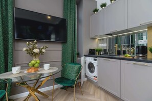 Fully equipped kitchenette with a kettle, fridge with freezer, microwave, coffee machine, washing machine and dining area.