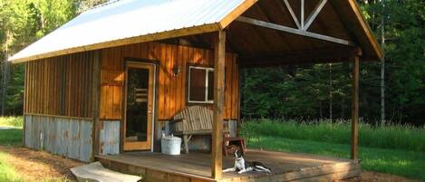 A view of the cabin in early summer with the host's dog, Beau, on the covered porch