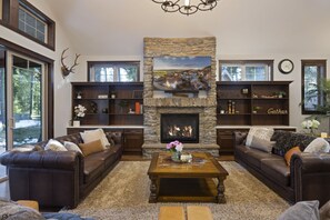 Stone Gas fireplace, tufted leather sofas, and soaring ceilings offer refined mountain lodge comfort with high-end rustic charm.