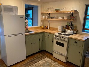 Small, tastefully designed kitchen. Electric stove, microwave, and toaster.