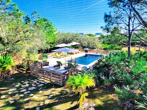 Elevated pool oasis with palms, grill, and lounge seating!