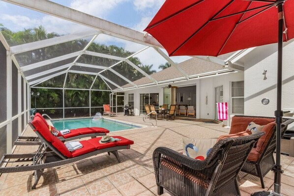 Fully screened pool area with loungers, conversational seating, outdoor dining and a gas grill